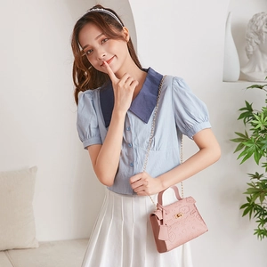 Detailed close-up of pink embossed faux leather Kelly bag with gold chain and twist lock