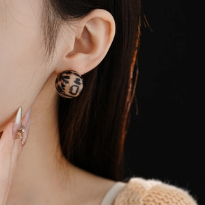 Close-up of leopard print ball stud earring worn by a model for a chic retro look