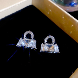 Close-up of silver purse-shaped earrings with large crystals in a black velvet box