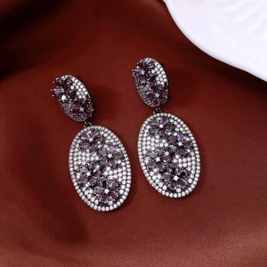 Macro shot of vintage style earrings with purple zircon flower clusters on silk