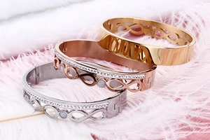 Close-up of double-row pavé infinity bangles in gold, rose gold and silver finishes