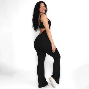 Side view of black backless jumpsuit with U-neck and flared pants on a smiling model