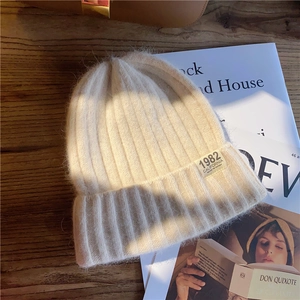 Close-up of beige knitted beanie with vintage 1982 California label on wooden background