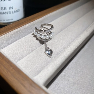 Détail d'un ear cuff triple couche avec zircon, perles et un pendentif en forme de cœur