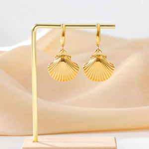 Elegant gold shell drop earrings displayed on a metal stand with a silk background