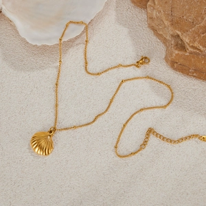 Golden shell pendant necklace for women on white beach sand with minimalist summer style