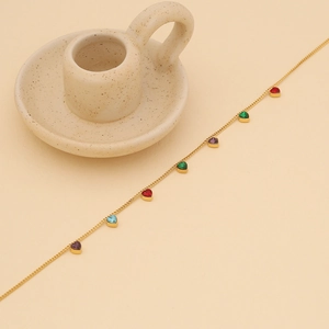 Close-up of golden stainless steel chain with colorful heart-shaped gems on soft background
