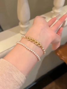 Detail showing elegant layered pearl bracelets with gold zircon-studded round links