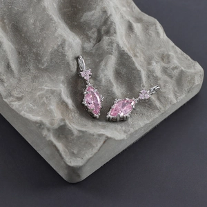 Macro shot of silver stud earrings featuring pear-cut pink zircon stones on grey stone