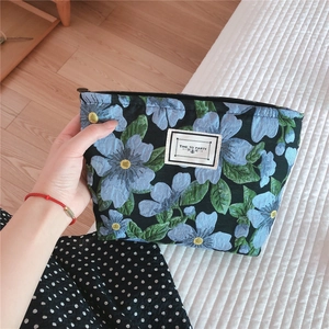 Detail of floral jacquard canvas makeup bag with blue flowers and TIME TO PARTY label