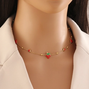 Collana dorata con ciondoli a fragola rossa e tondi indossata da una modella