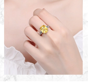 Close-up of a silver ring featuring a large yellow square-cut gem and side diamonds