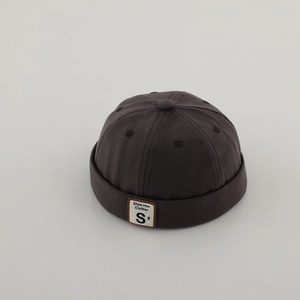 Dettaglio del berretto docker grigio scuro in cotone con etichetta S e bordo arrotolato