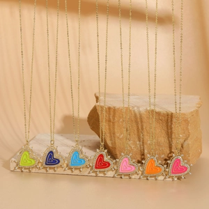 Macro shot of colorful enamel heart pendants with zircon inlay on natural stone props