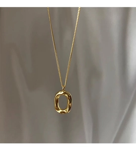 Detail of minimalist 925 silver golden necklace with irregular oval donut pendant texture