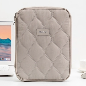 Macro shot of quilted grey tablet sleeve with protective padding and metal brand logo