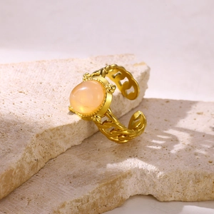 Detailed shot of retro gold-plated ring with orange stone on natural textured stone base