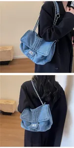 Detail of vintage denim tote with silver chain strap on a black coat model