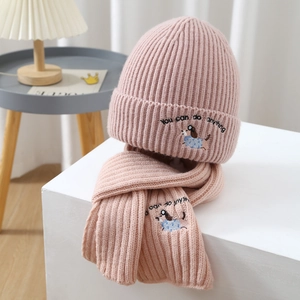 Close-up of pink knitted hat and scarf set featuring dog embroidery and motivational text