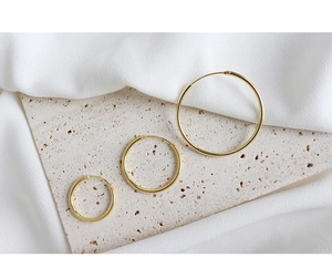 Detailed macro view of three different sized minimalist gold S925 sterling silver hoop earrings