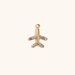 Macro detail of gold airplane pendant with shimmering zircon wing inlays for jewelry DIY