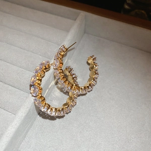 Macro view of gold hoop earrings featuring sparkling pave-set rhinestones in a luxury tray