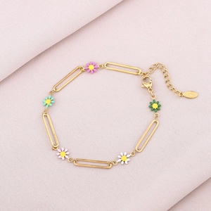 Detail of gold stainless steel bracelet with five colorful enamel daisy charms on a pink cloth