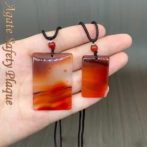 Handheld display of two red agate rectangular pendants with traditional woven cords