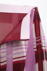Detail shot of sheer red and pink plaid fabric with a white waistband and zipper closure
