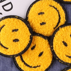 Yellow chenille smiley face patch with black embroidery on blue denim background