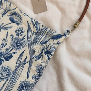 Detail of vintage blue floral cotton bag with brown cord strap and brass hardware