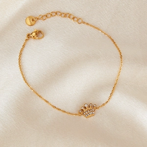 Elegant gold stainless steel bracelet with a sparkling crown pendant on silk background