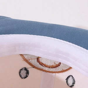 Detail view showing blue fabric stitching and sweatband of a cartoon bear baby cap