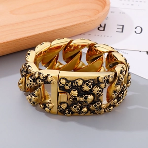 Détail d'un bracelet punk doré massif avec des gravures de crânes en relief détaillées