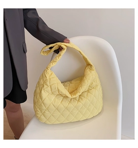 Detail of soft quilted puffer bag in yellow on a chair showing its large capacity texture