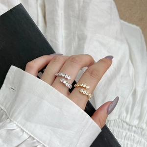 Detail of adjustable silver and gold rings with emerald and round cut zircons on fingers