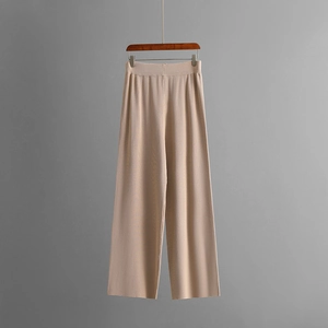 Detail of warm beige knitted wide-leg trousers with soft vertical drape texture