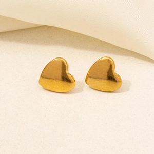 Close-up of golden heart-shaped 304 stainless steel stud earrings on beige fabric