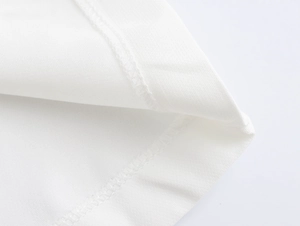 Detailed view of professional hemming and textured white fabric on elegant trousers