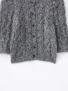 Macro detail of grey cable knit texture and black buttons on this knitted cardigan