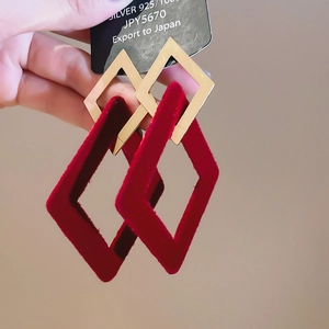 Close-up of red flocked diamond earrings with gold geometric metal frame and 925 silver tag