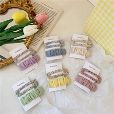 Close-up of assorted floral fabric hair clips in purple, pink and yellow sets