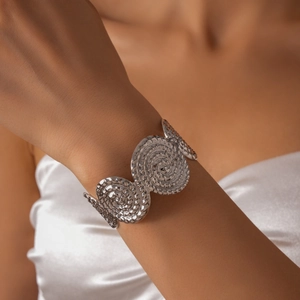 Détail du bracelet manchette plissé argenté avec des textures métalliques spirales