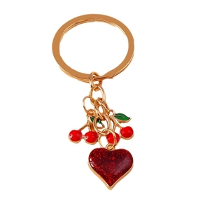Golden keychain with red glitter heart and enamel cherry pendants on white background