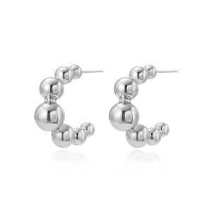 Macro detail of high-shine silver hollow bead C-shaped hoop earrings with metallic finish