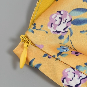 Detailed macro view of the seamless invisible zipper on yellow floral silk dress fabric