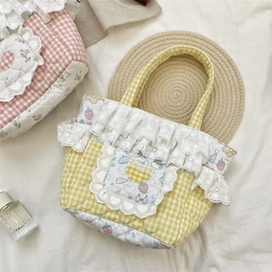 Close-up of quilted yellow checkered handbag featuring white lace edges and cute strawberry patterns