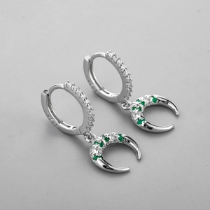 Détail de boucles d'oreilles lune en argent S925 avec zircons blancs et verts sur fond gris