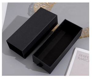 Detail shot of a black cardboard drawer-style gift box with a magazine and golden plate