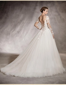 Dettaglio delle eleganti maniche in pizzo e schiena a V con bottoni su un abito da sposa bianco